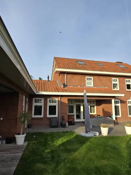 Achtertuinen van rijwoningen met schoongemaakte ramen en kozijnen aan de tuinzijde